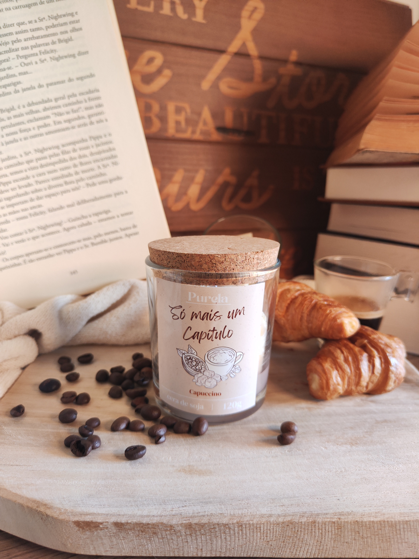 Vela Só mais um Capítulo Vela perfumada Purela com tampa de cortiça e croissants ao lado de livros e café