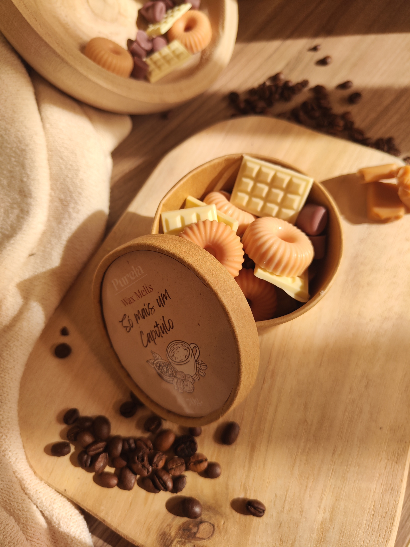Wax Melt Só mais um Capítulo Caixa redonda com wax melts em formas de chocolate e shapes redondos, sobre madeira com grãos de café.