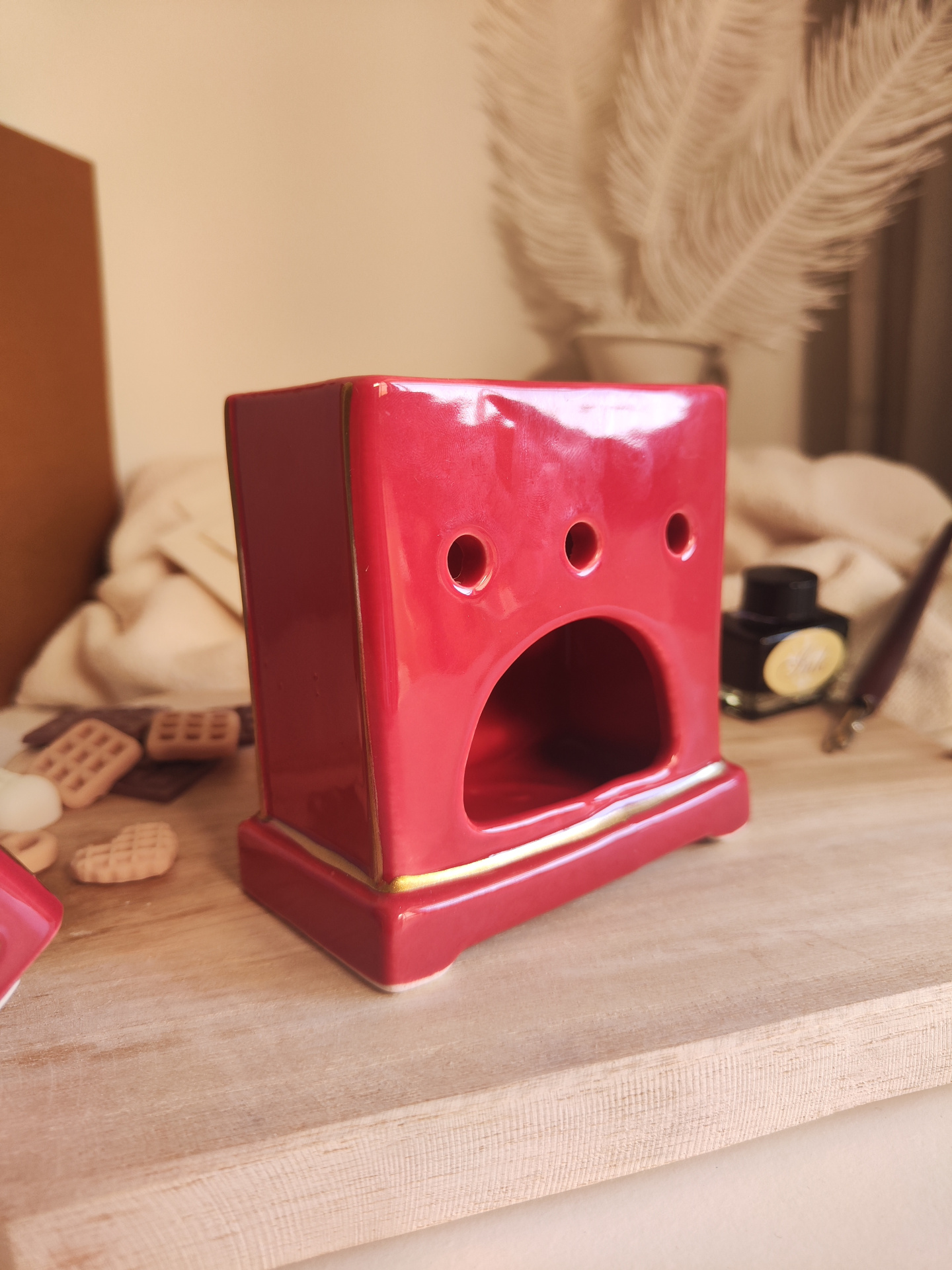 Queimador Cartas ao Pai Natal Aromatizador cerâmico vermelho com detalhes dourados e aberturas, sobre mesa de madeira