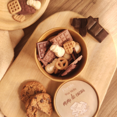 Vela aromática mimo de cacau com cookies e chocolates em cima de tábuas de madeira