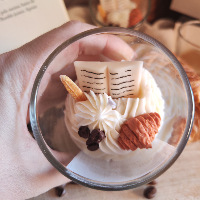 Sobremesa em taça com chantilly, livro em chocolate branco, cone castanho e gotas de chocolate.