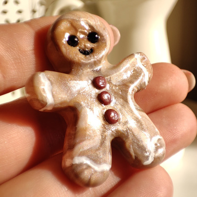 Boneco de gengibre cerâmico castanho claro com detalhes em branco e botões vermelhos.