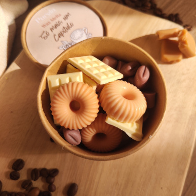 caixa de cartão com velas de cera e grãos de café sobre mesa de madeira clara