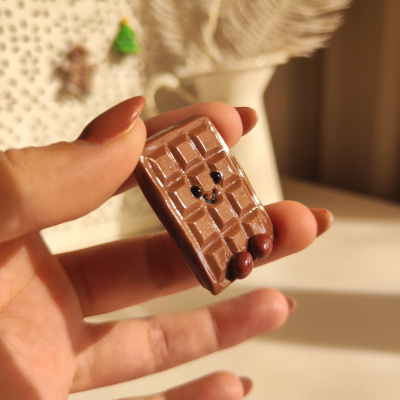 Pequeno objeto decorativo em forma de barra de chocolate sorridente com olhos pretos