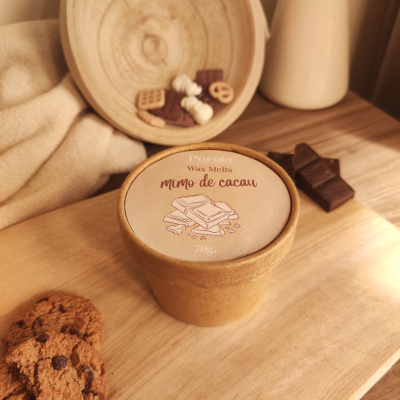 Embalagem de Wax Melts mimo de cacau em cartão castanho com rótulo, bolachas e barra de chocolate sobre mesa de madeira.