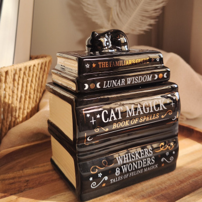 Conjunto de caixas em cerâmica em forma de livros mágicos com ouro e branco, com gato preto no topo.