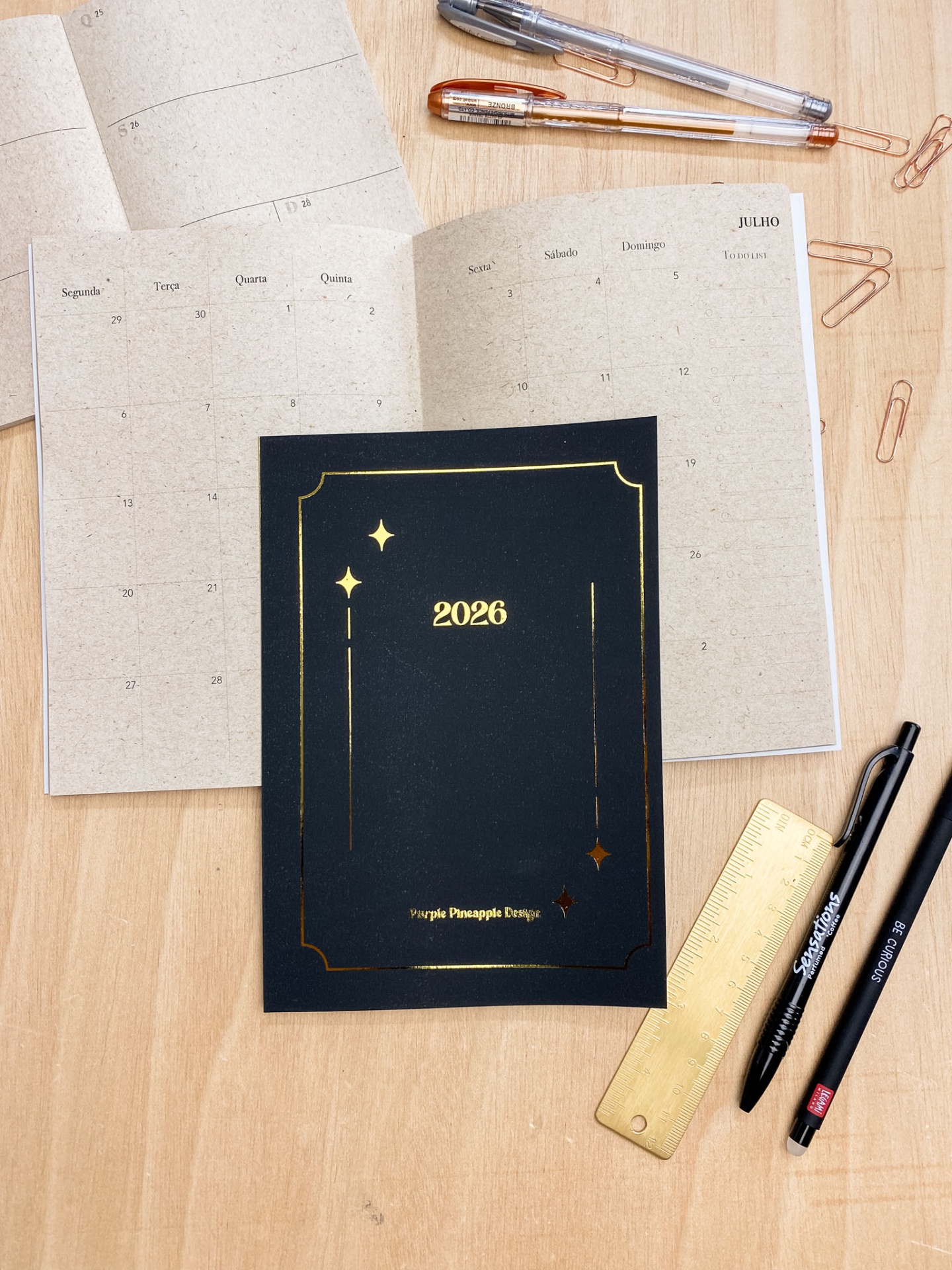 Agenda 2026 preta aberta sobre mesa com acessórios de escrita