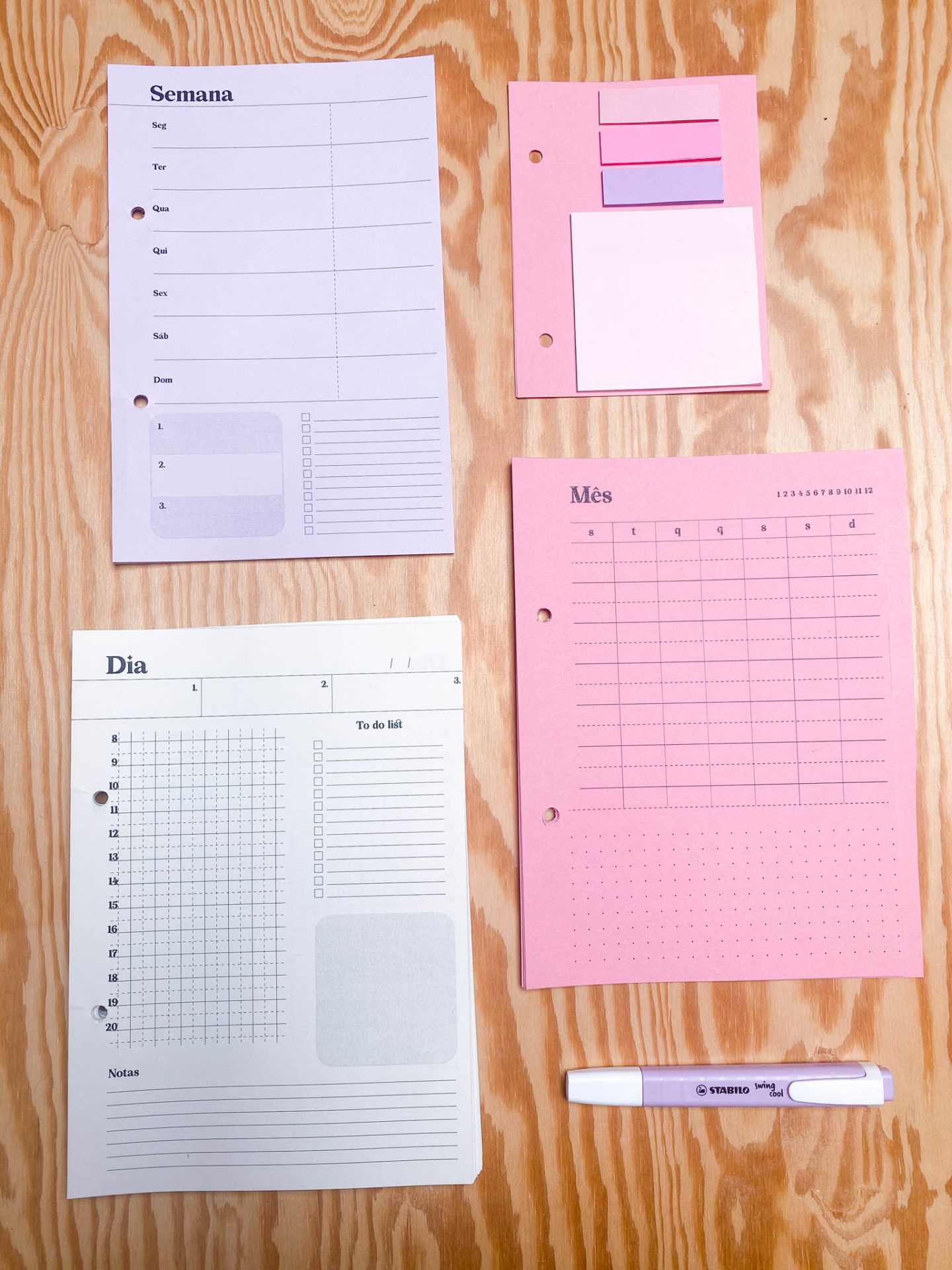 Conjunto de papelaria para organização com folhas de planeamento e caneta sobre madeira