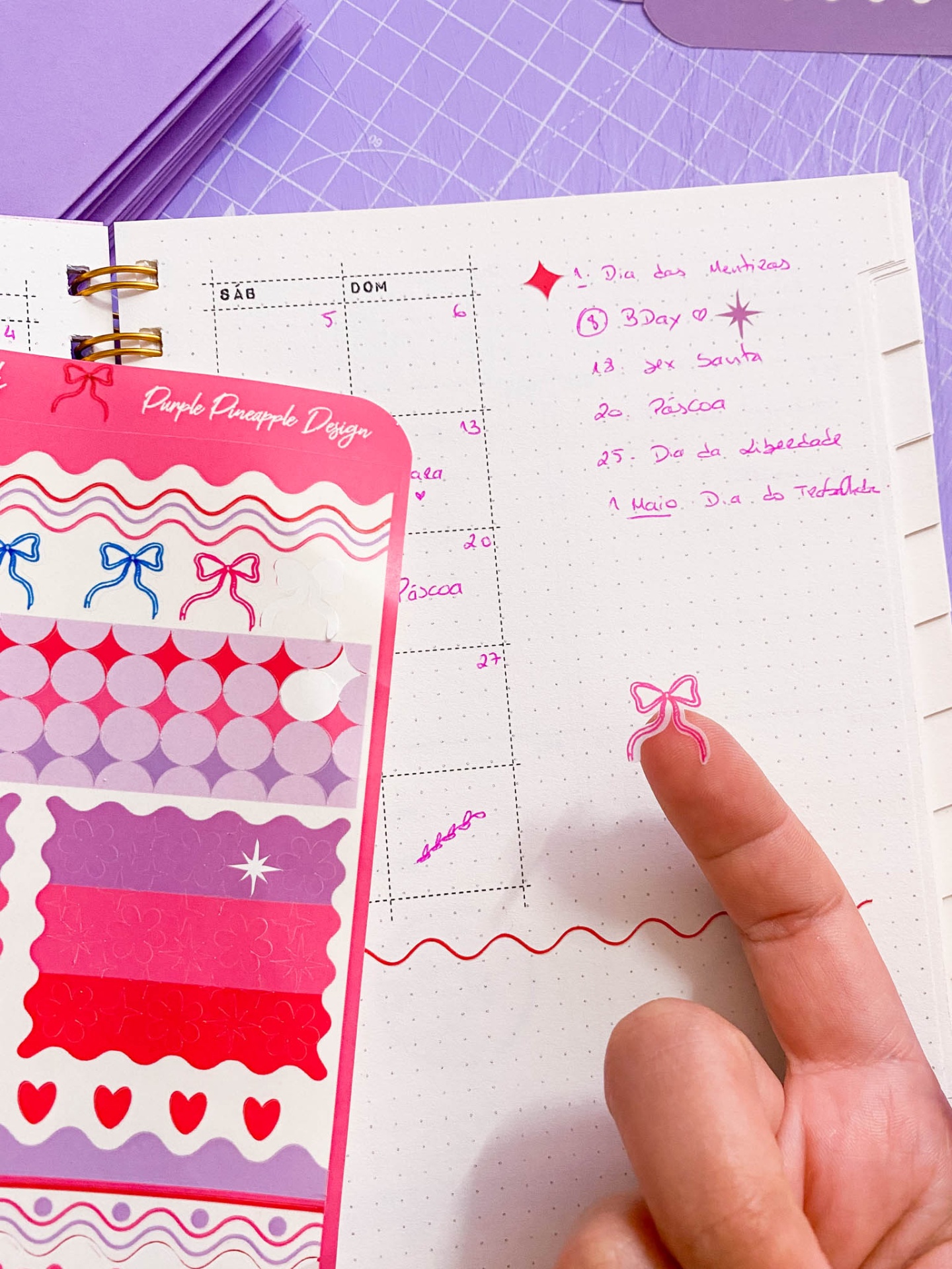 Bloco de autocolantes coloridos e caderno pontilhado com anotações em rosa