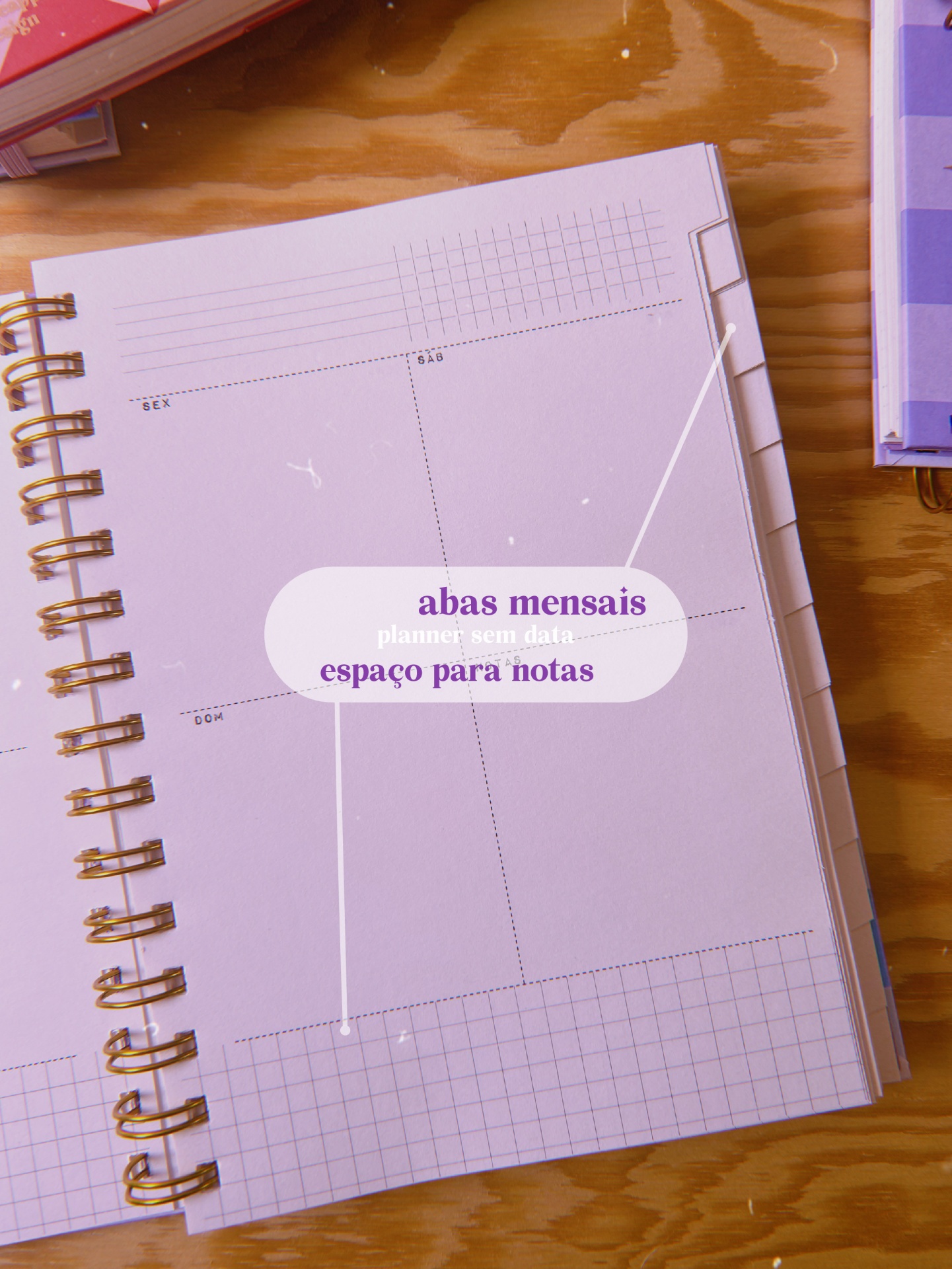 Planner semanal com abas mensais e espaço para notas sobre mesa de madeira