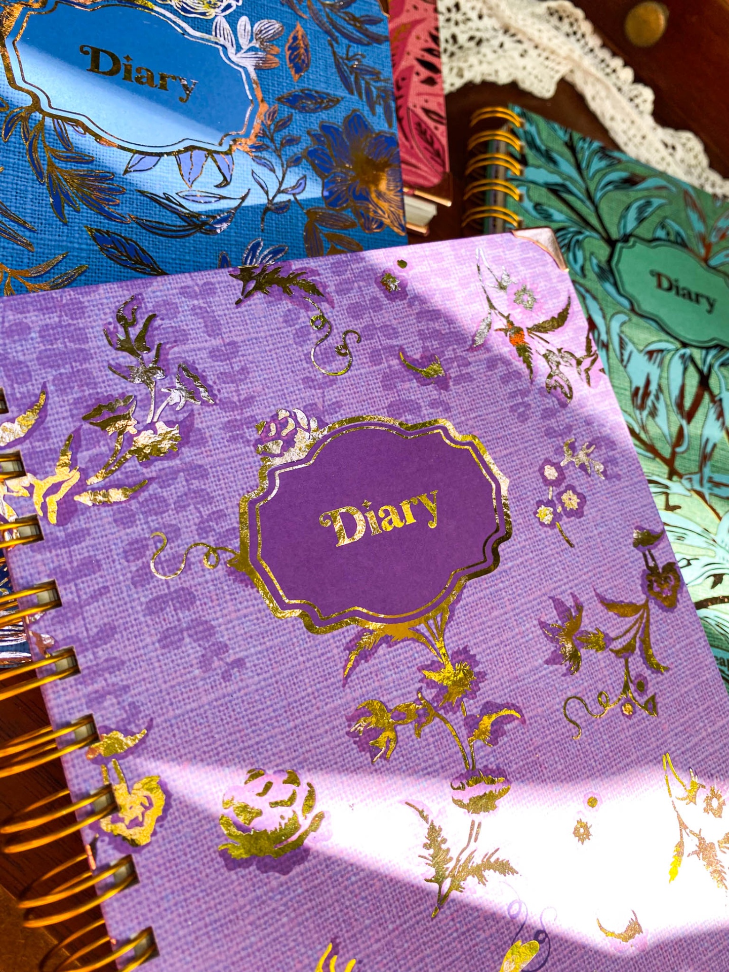 Cadernos tipo diário com capas coloridas e detalhes dourados