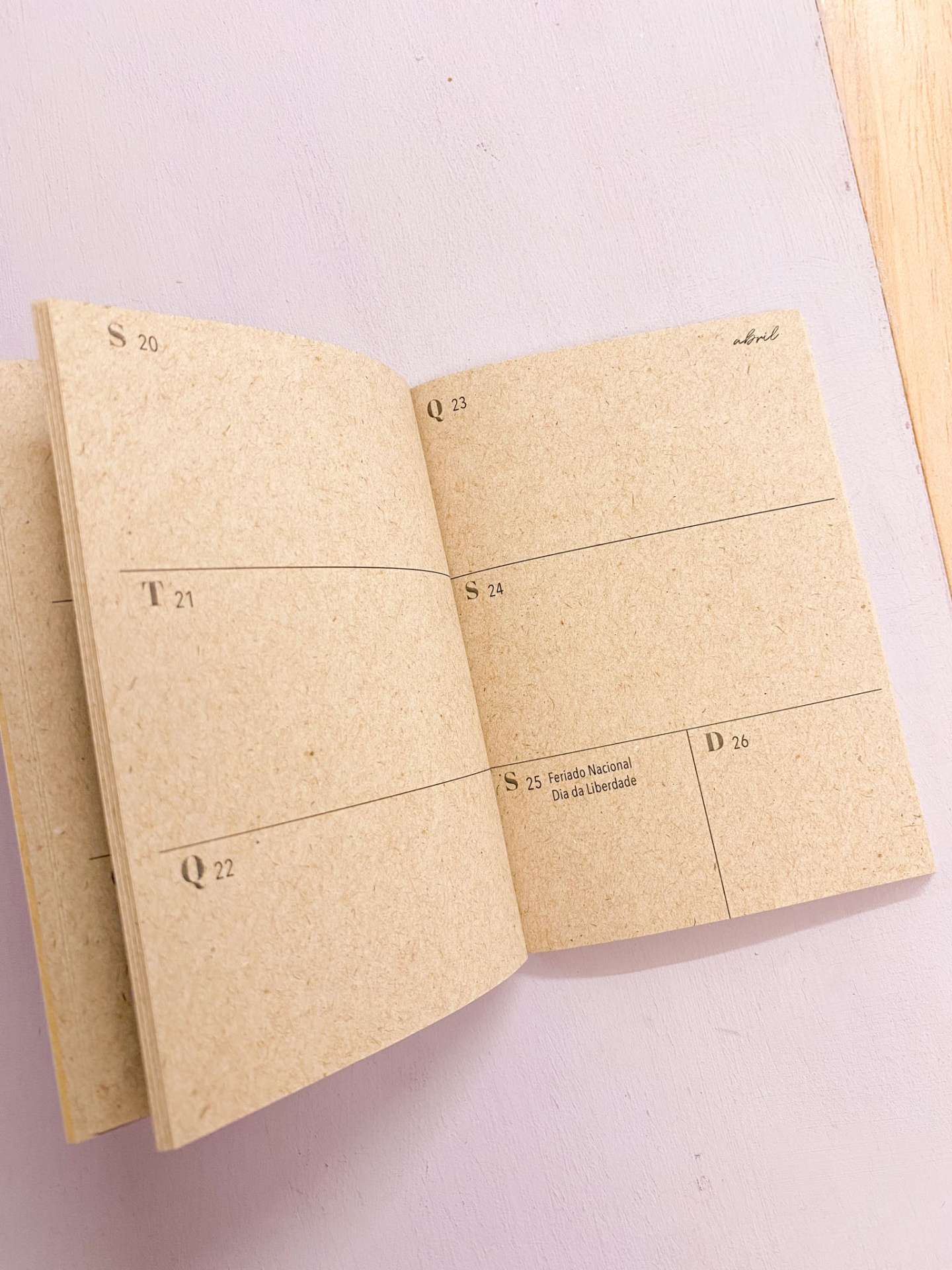 Agenda semanal aberta com páginas de papel reciclado e datas impressas.