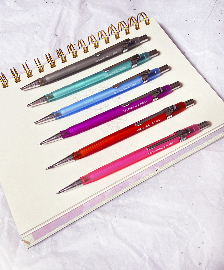 Seis canetas mecânicas coloridas alinhadas em caderno espiral aberto
