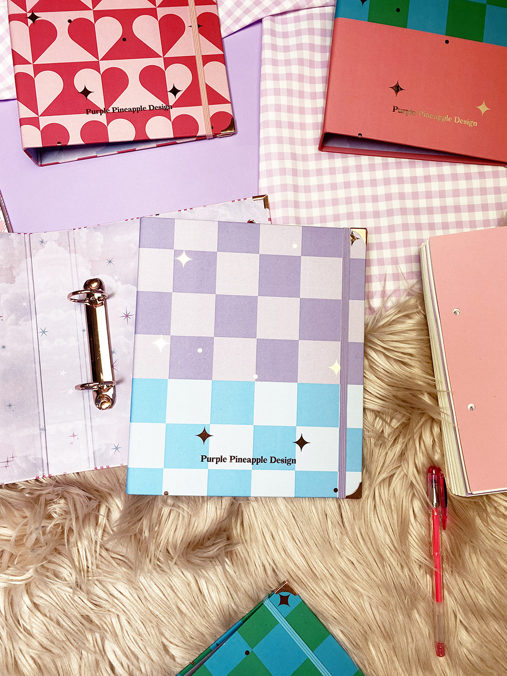 Cadernos coloridos com padrões geométricos e texto Purple Pineapple Design sobre tecidos e pelo sintético