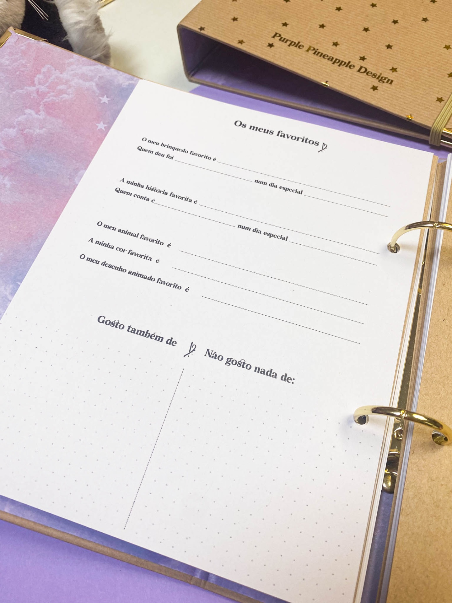 Caderno aberto com página de perguntas em português e capa castanha com texto Purple Pineapple Design