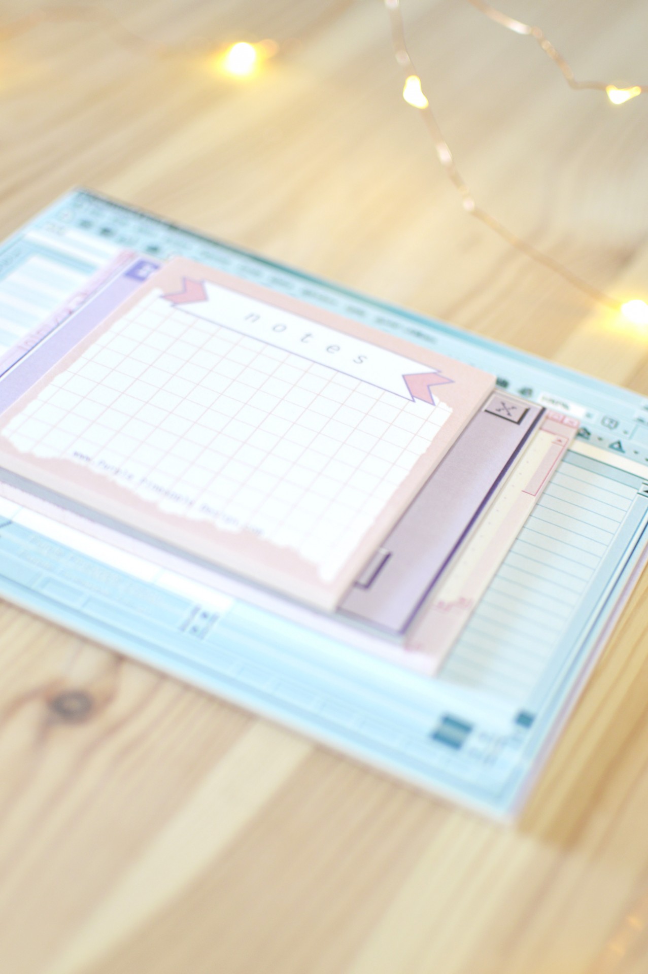 Conjunto de blocos de notas coloridos com papel quadriculado e listas sobre superfície de madeira clara