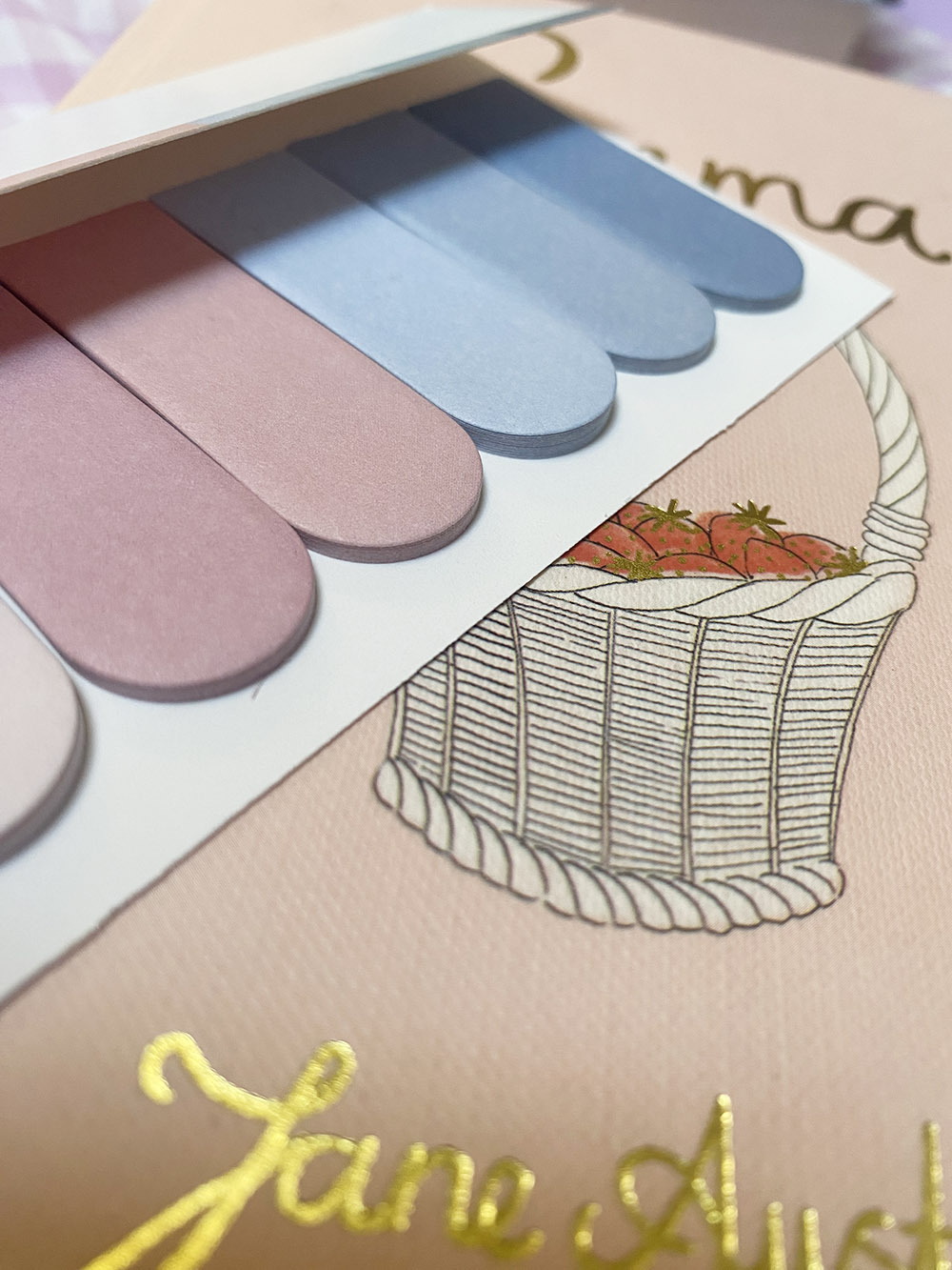 Paleta de amostras pastel sobre fundo com ilustração de cesto e texto dourado