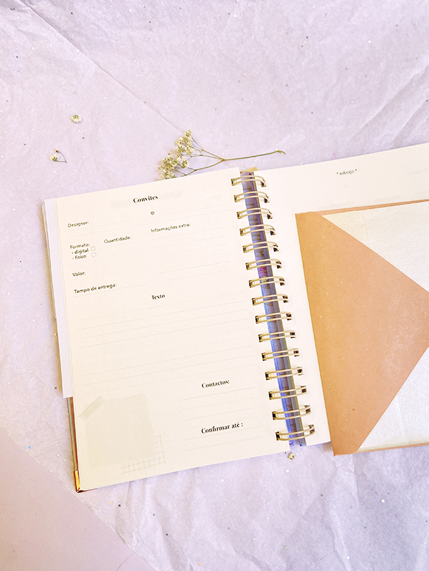 Caderno espiral aberto com páginas de organização e folhas secas ao lado.