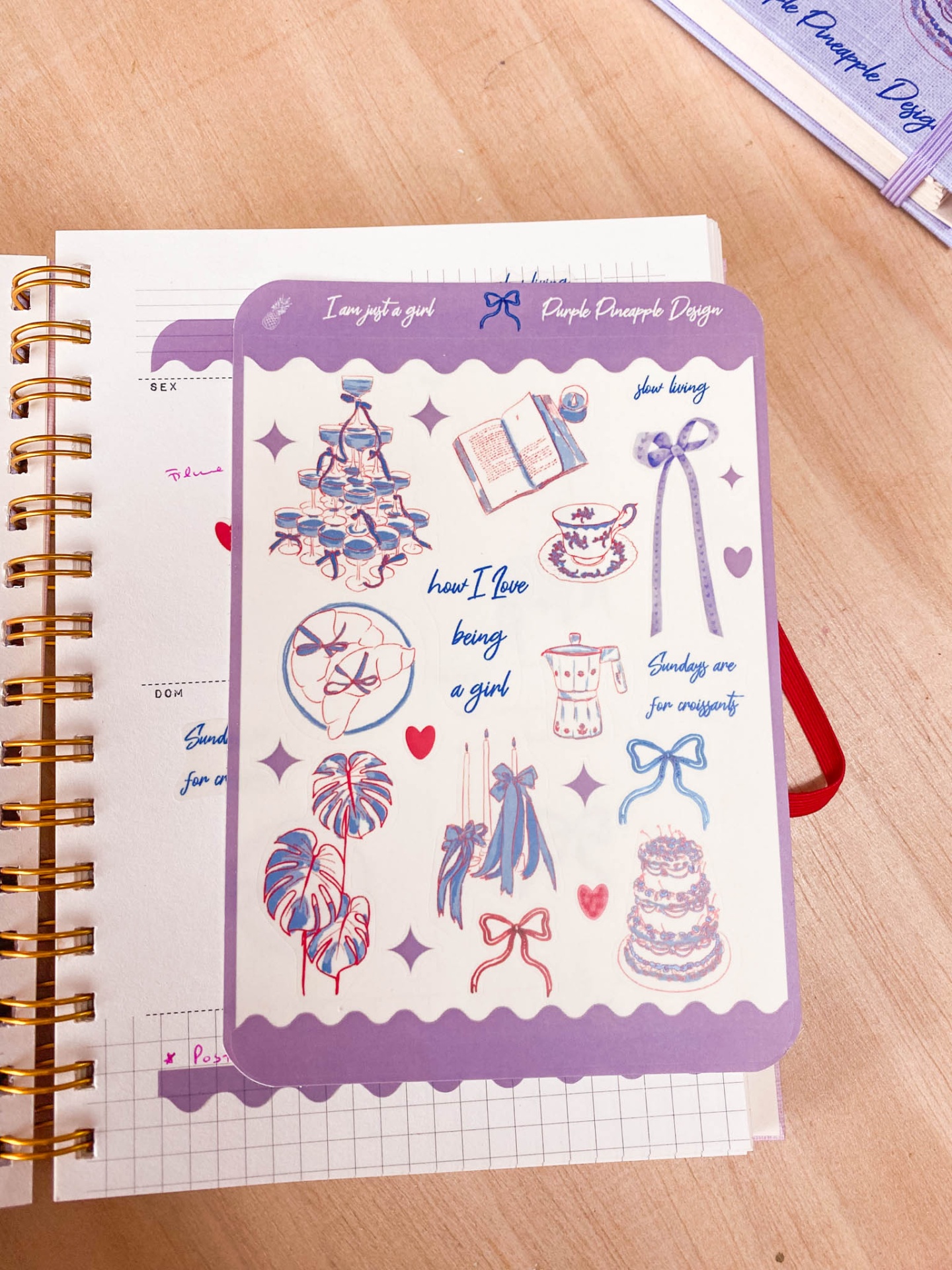 Cartão decorativo roxo e branco com ilustrações e texto colocado sobre agendas.