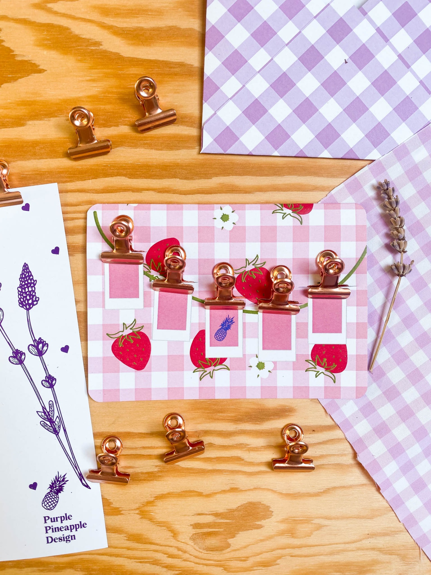 Produtos de papelaria com clips dourados e cartões decorativos sobre madeira clara