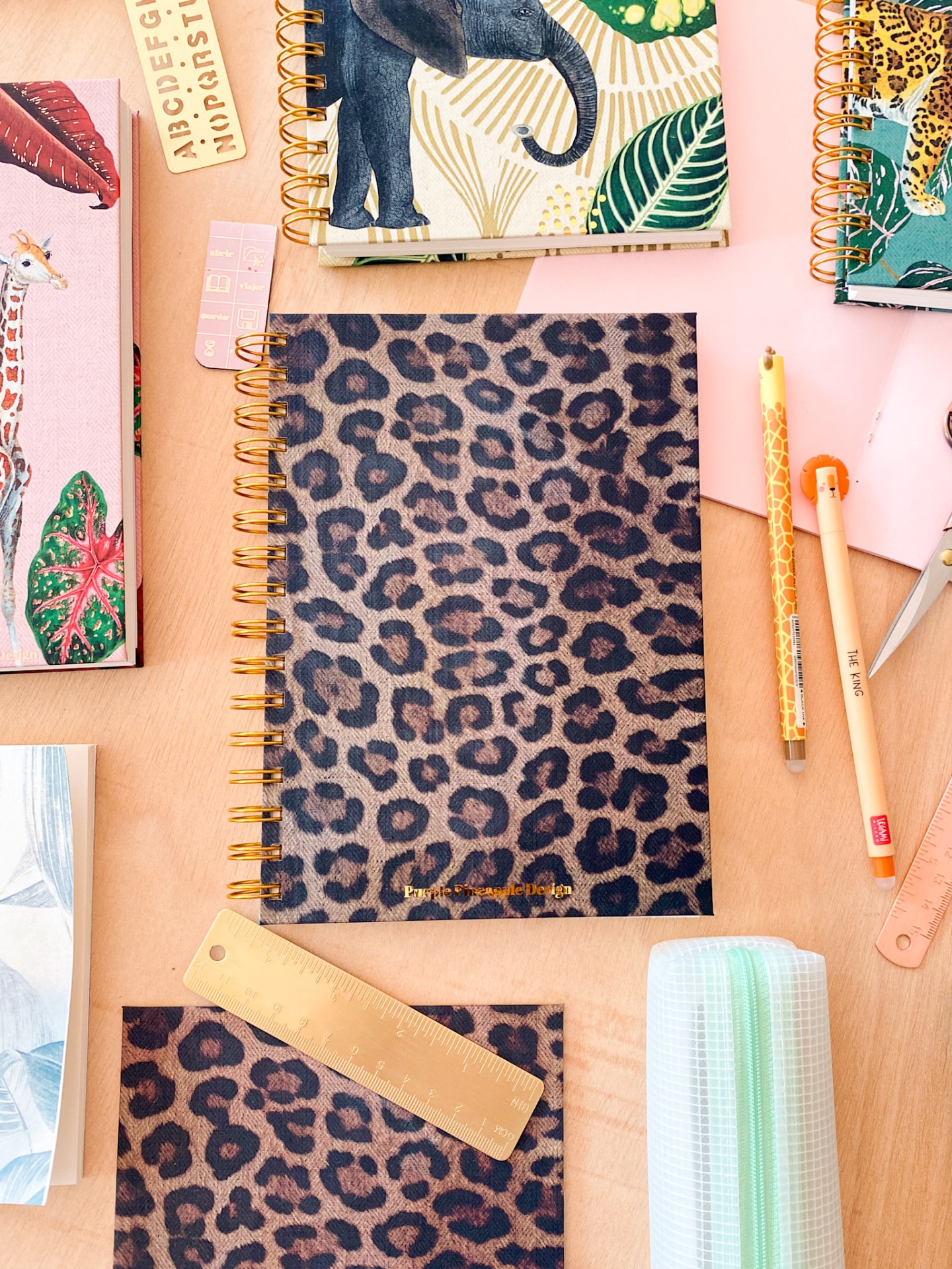 Cadernos espiral com capas de animais e padrões coloridos sobre uma mesa de madeira clara.