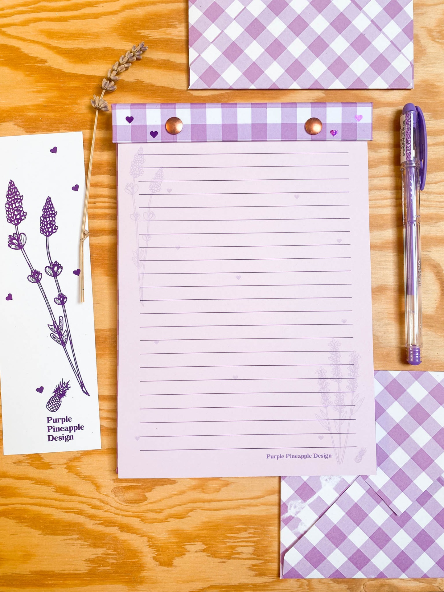 Conjunto de papelaria lilás com bloco de notas, envelope, marcador, caneta e flores secas