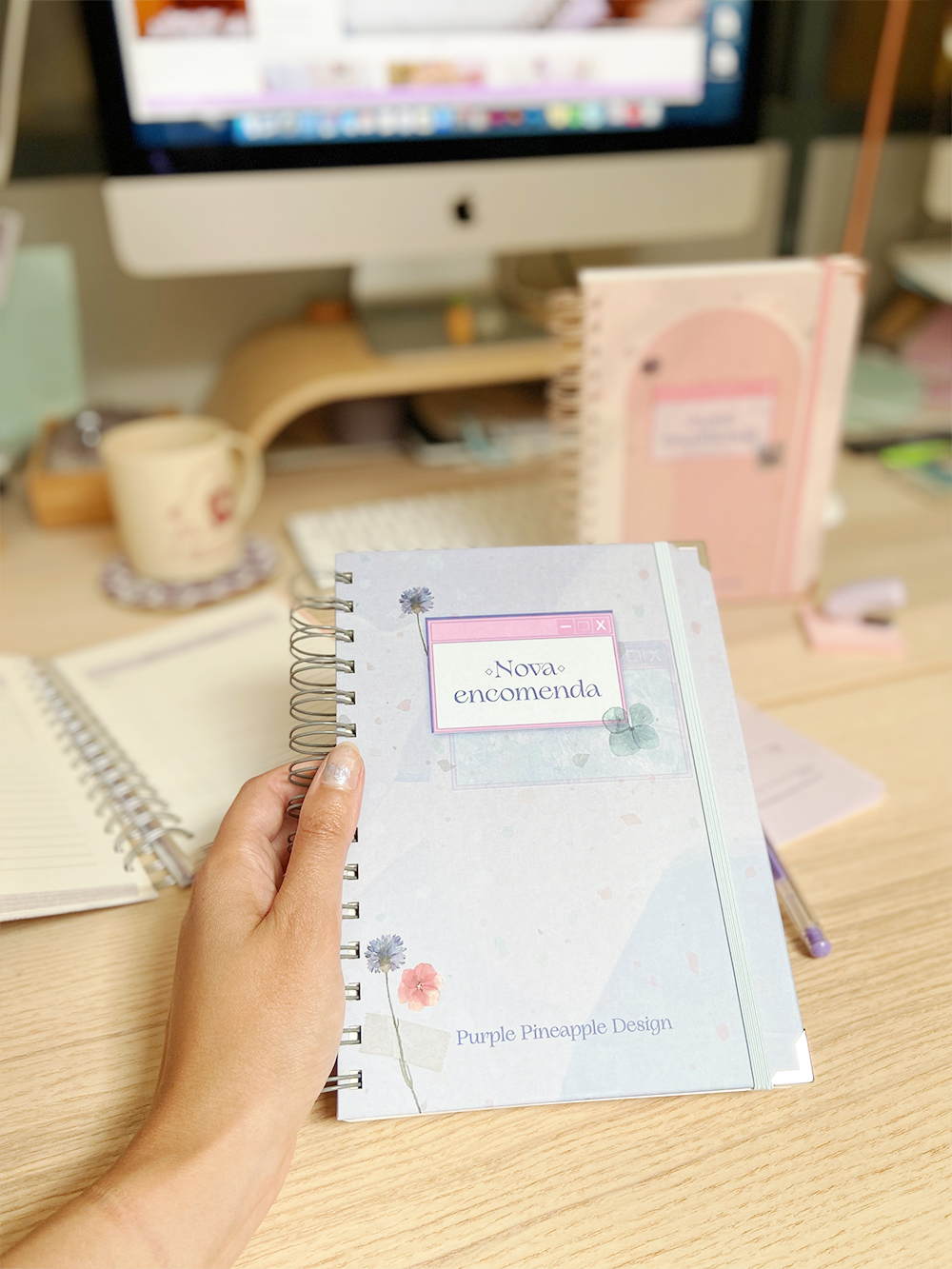 Caderno azul claro com etiqueta 'Nova encomenda' em mesa de madeira