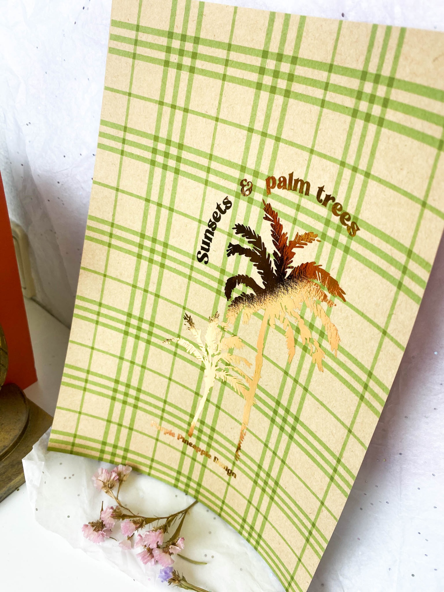 Cartão decorativo com padrão verde e ilustração de palmeiras e texto dourado