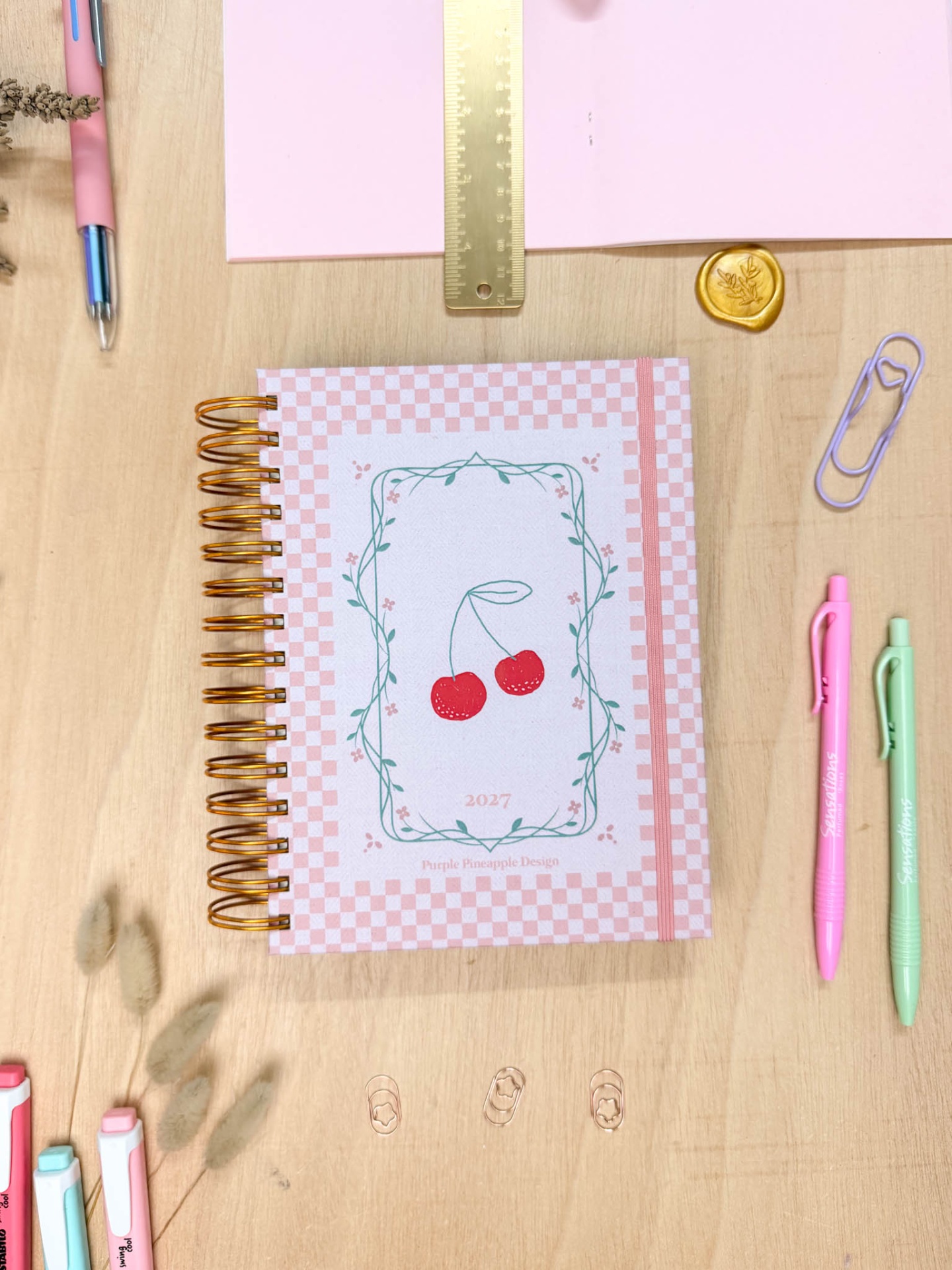 Caderno espiral com capa rosa e branca decorada com cerejas vermelhas e moldura verde