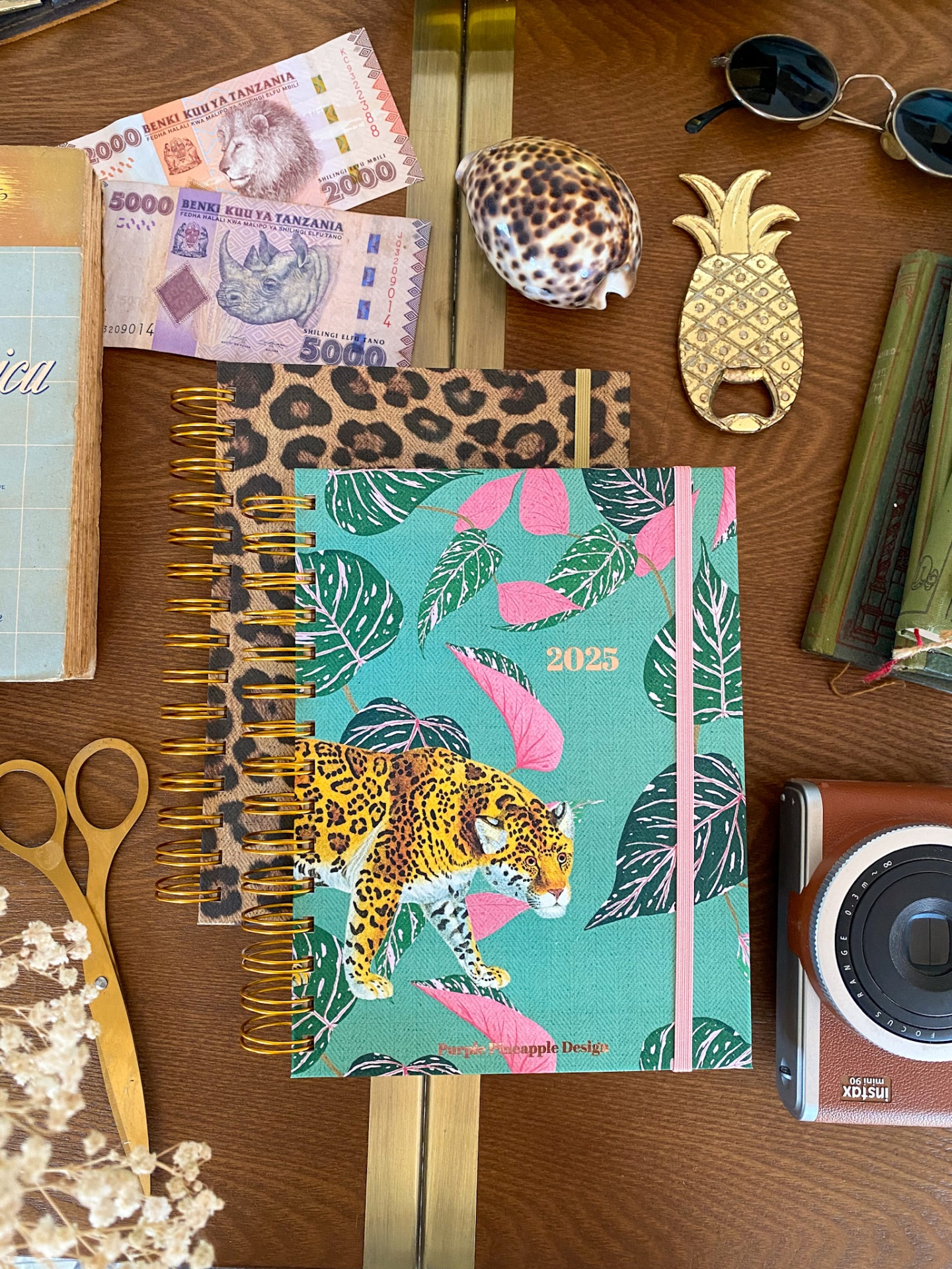 Dois agendas com capas animais e acessórios diversos sobre mesa de madeira