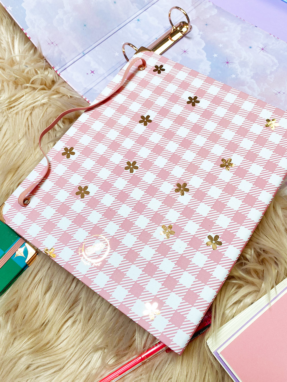 Pasta organizadora com padrão xadrez rosa e branco decorada com flores douradas