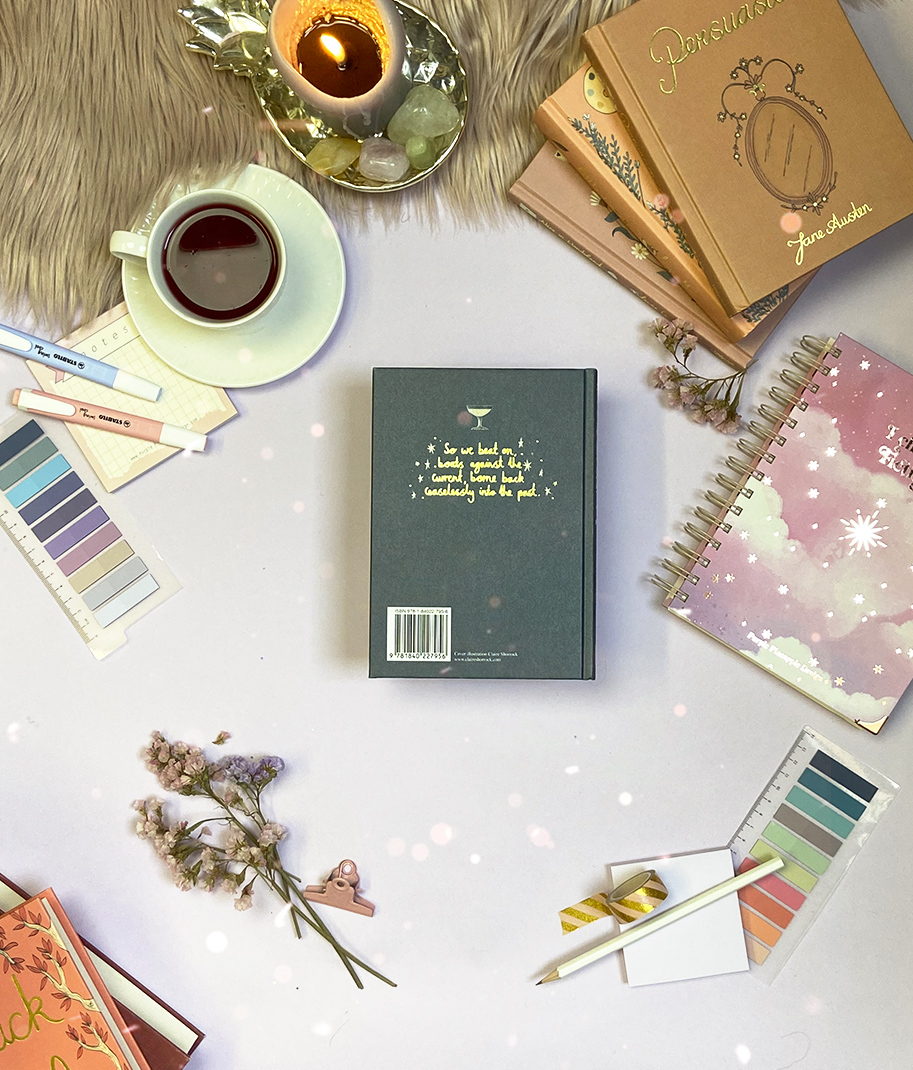 Mesa com cadernos, livro, paletas de cores, chávena de café, vela e flores secas