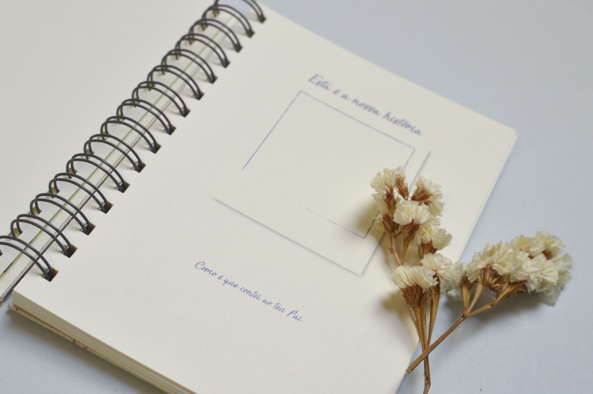 Caderno espiral aberto com texto e flores secas ao lado