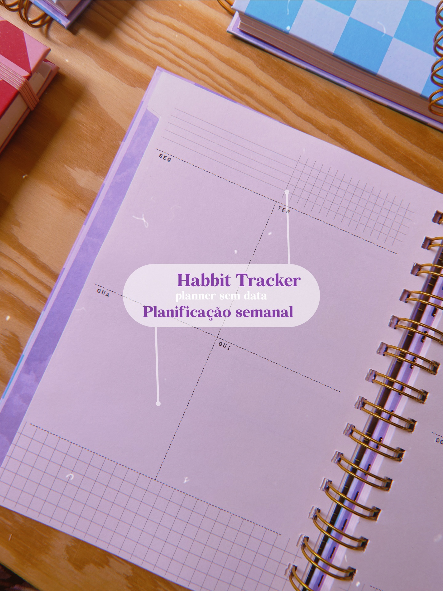 Página de planner semanal lilás com texto Habbit Tracker e espiral dourada sobre mesa de madeira