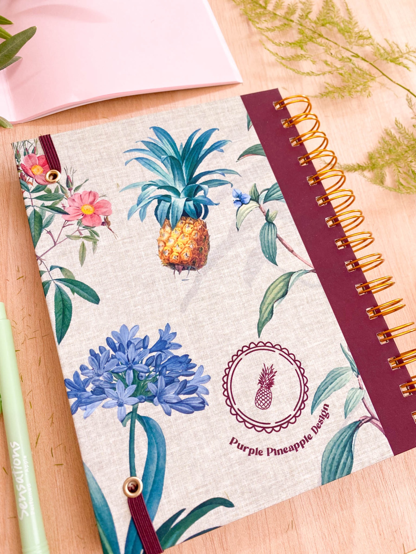 Caderno com capa estampada, espiral dourada e elástico vinho
