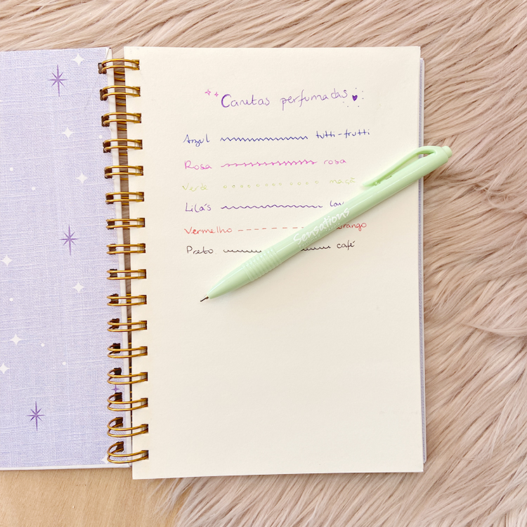 Caderno aberto com escrita colorida e caneta verde claro sobre fundo felpudo bege