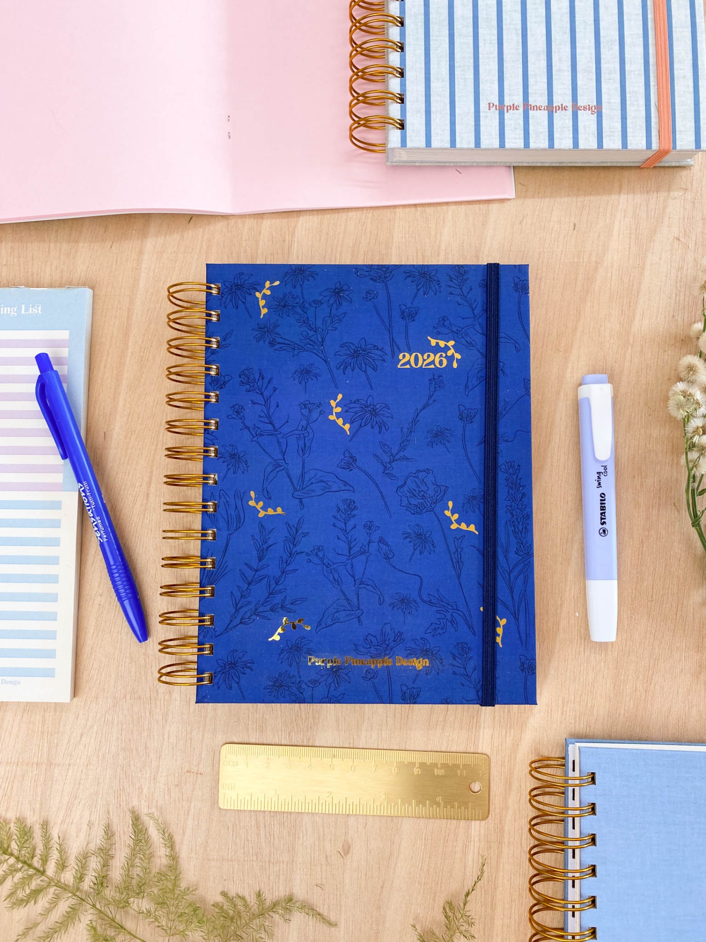 Caderno azul com espiral dourado e texto '2026' e 'Piecegreen Graphic Design'