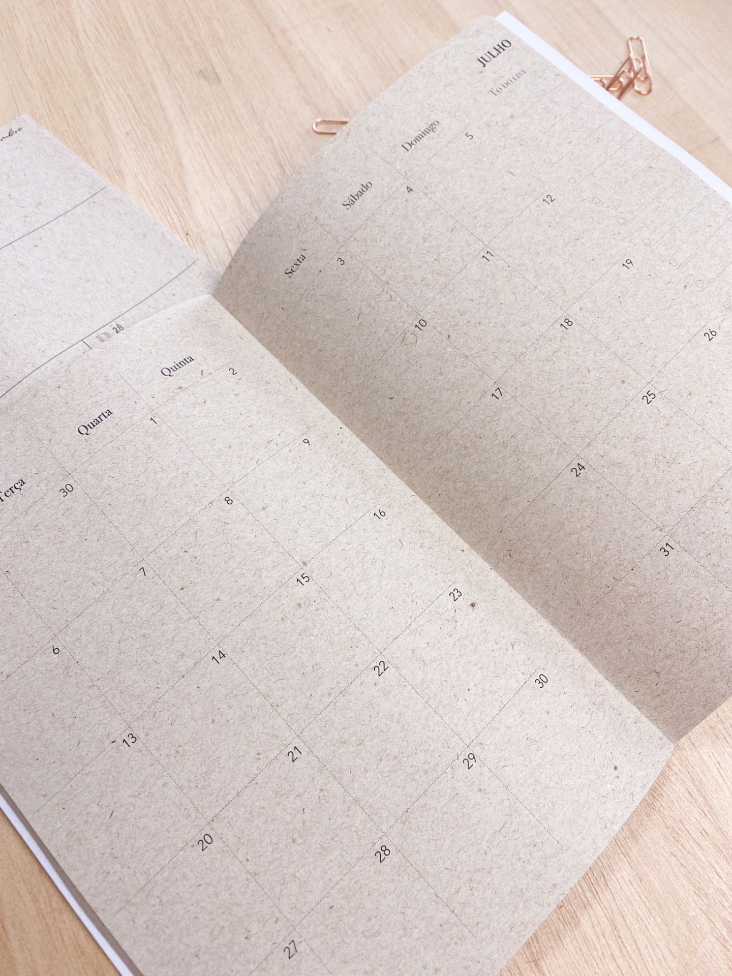 Calendário mensal em papel bege natural para o mês de julho sobre mesa de madeira clara