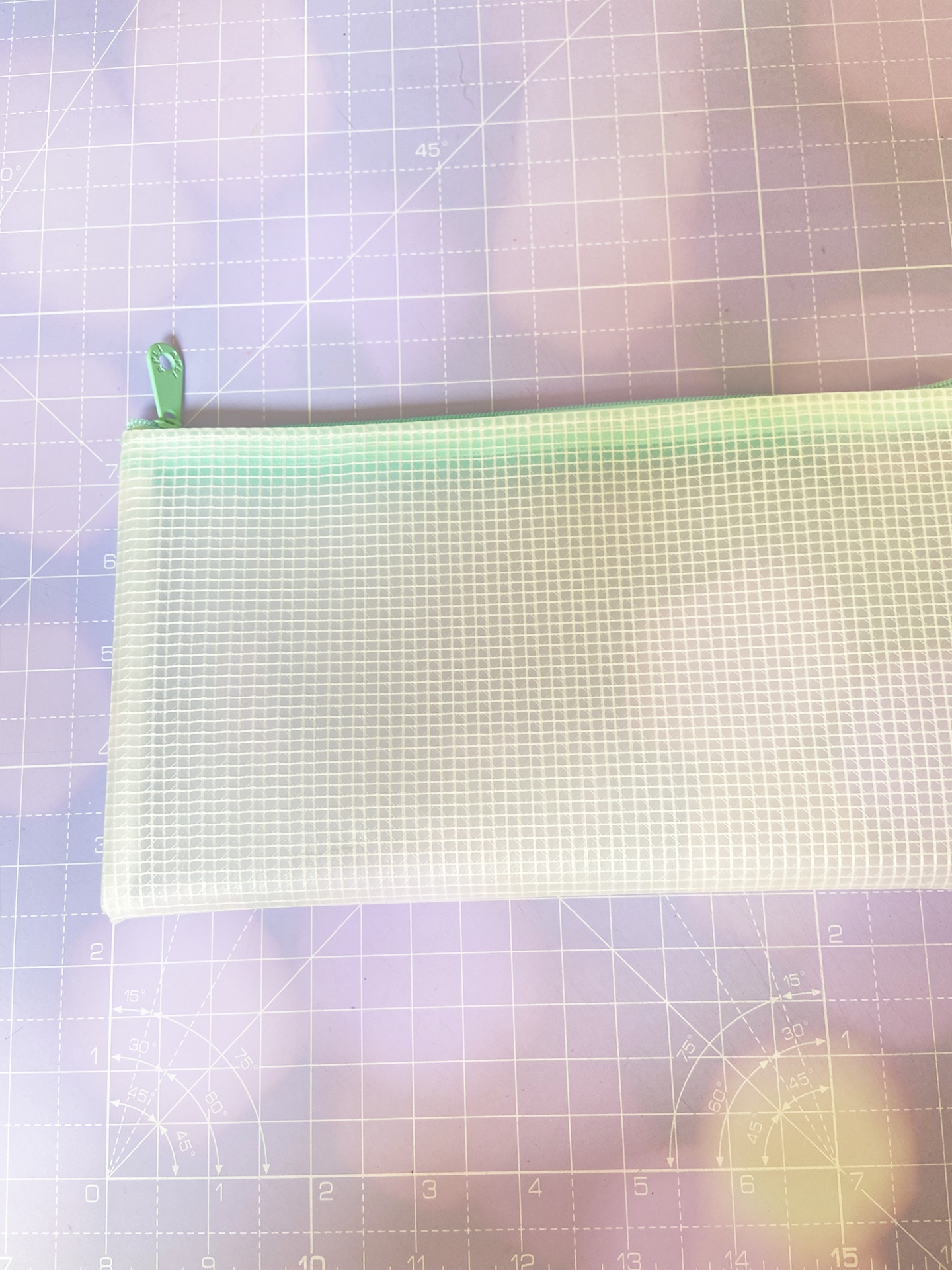 Bolsa transparente retangular com fecho verde em superfície lilás