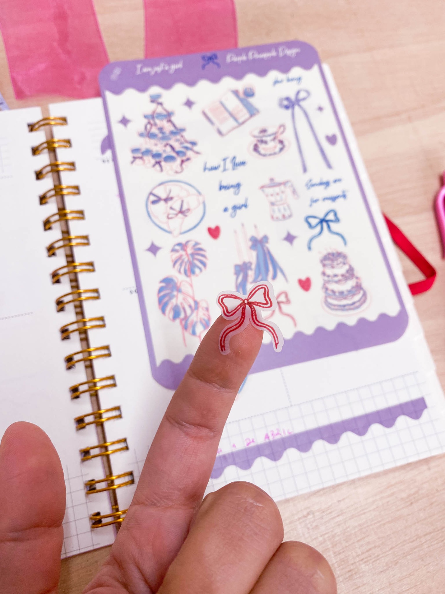 Adesivo de laço vermelho no dedo com caderno e folha decorada ao fundo