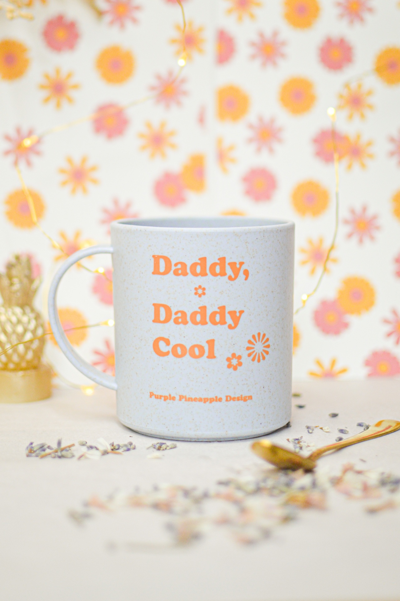 Caneca branca com texto laranja e decoração floral em fundo floral colorido