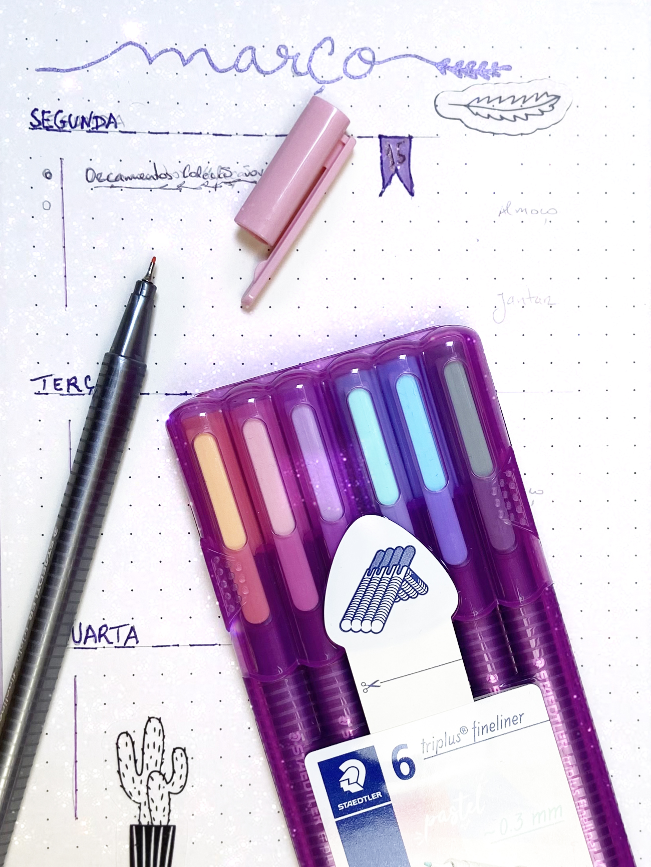 Pacote de 6 canetas fineliner em cores coloridas sobre papel com calendário desenhado à mão.