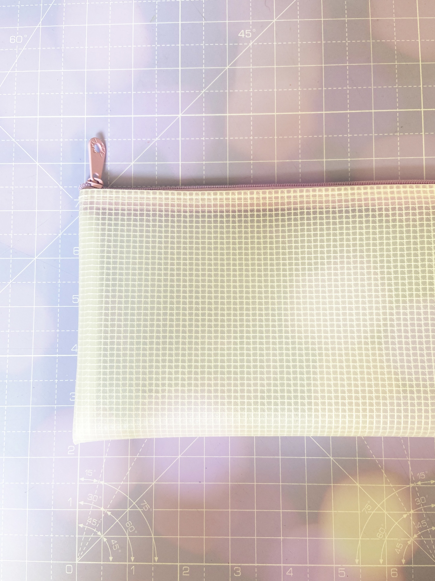 Bolsa branca quadriculada com fecho rosa sobre superfície de corte