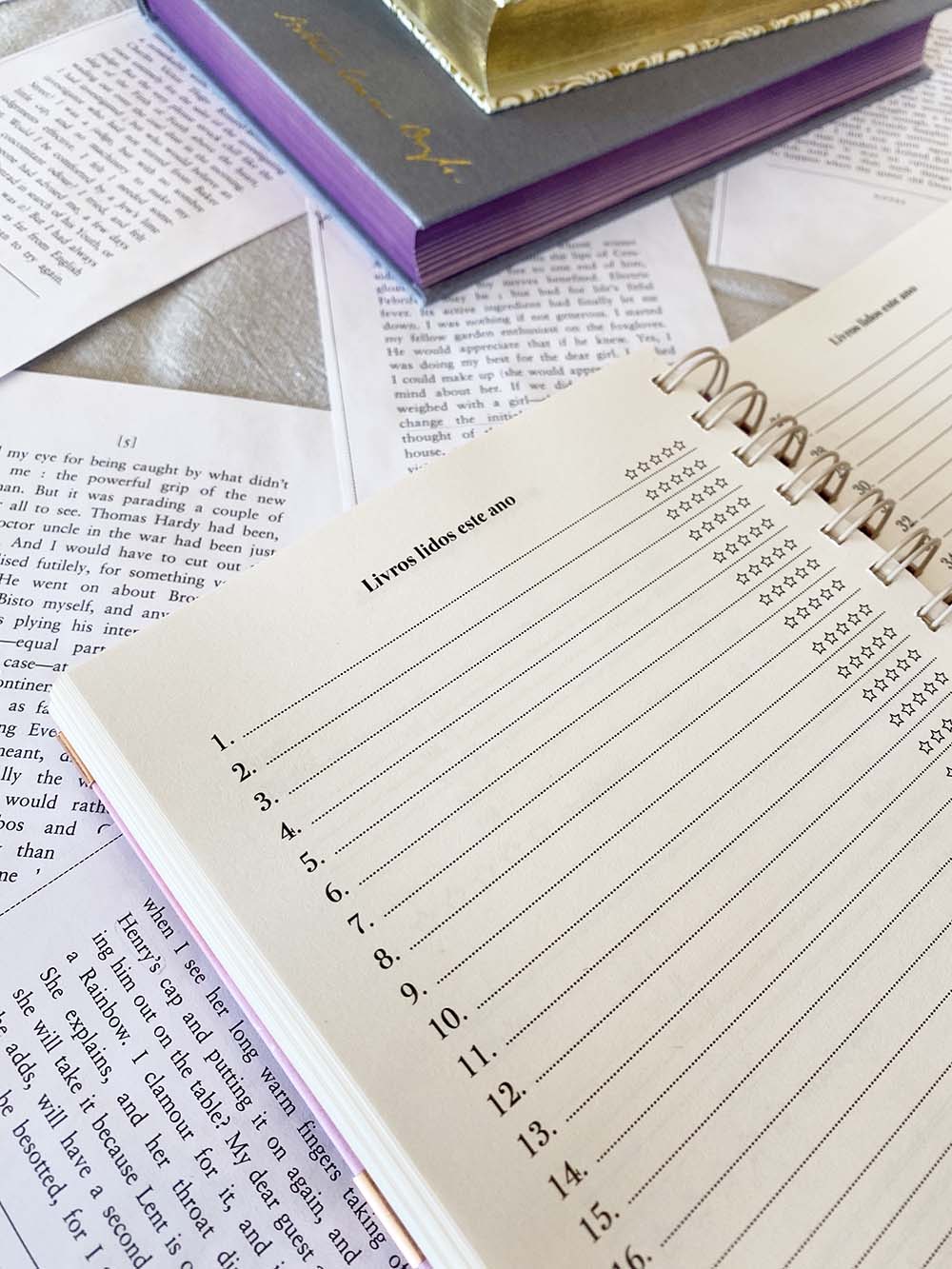 Agenda branca espiral com colunas de datas e estrelas entre livros e papéis soltos