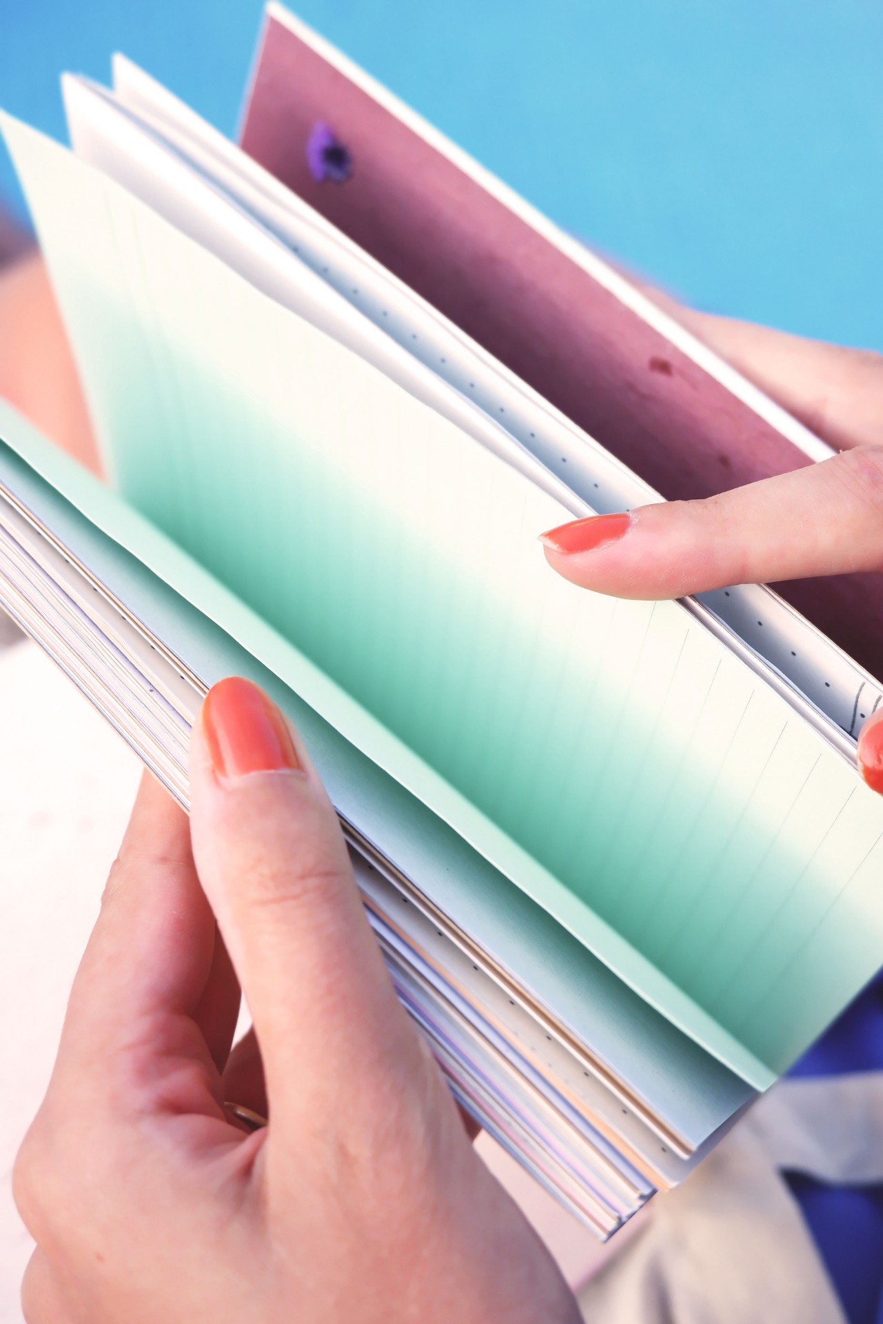 Mãos a segurar cadernos de várias cores com páginas abertas