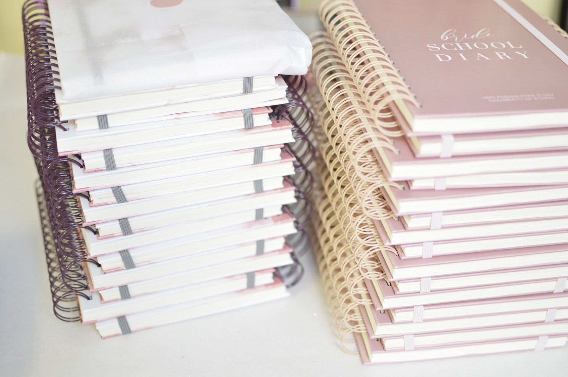 Duas pilhas de cadernos espirais empilhados em cores branco e rosa claro