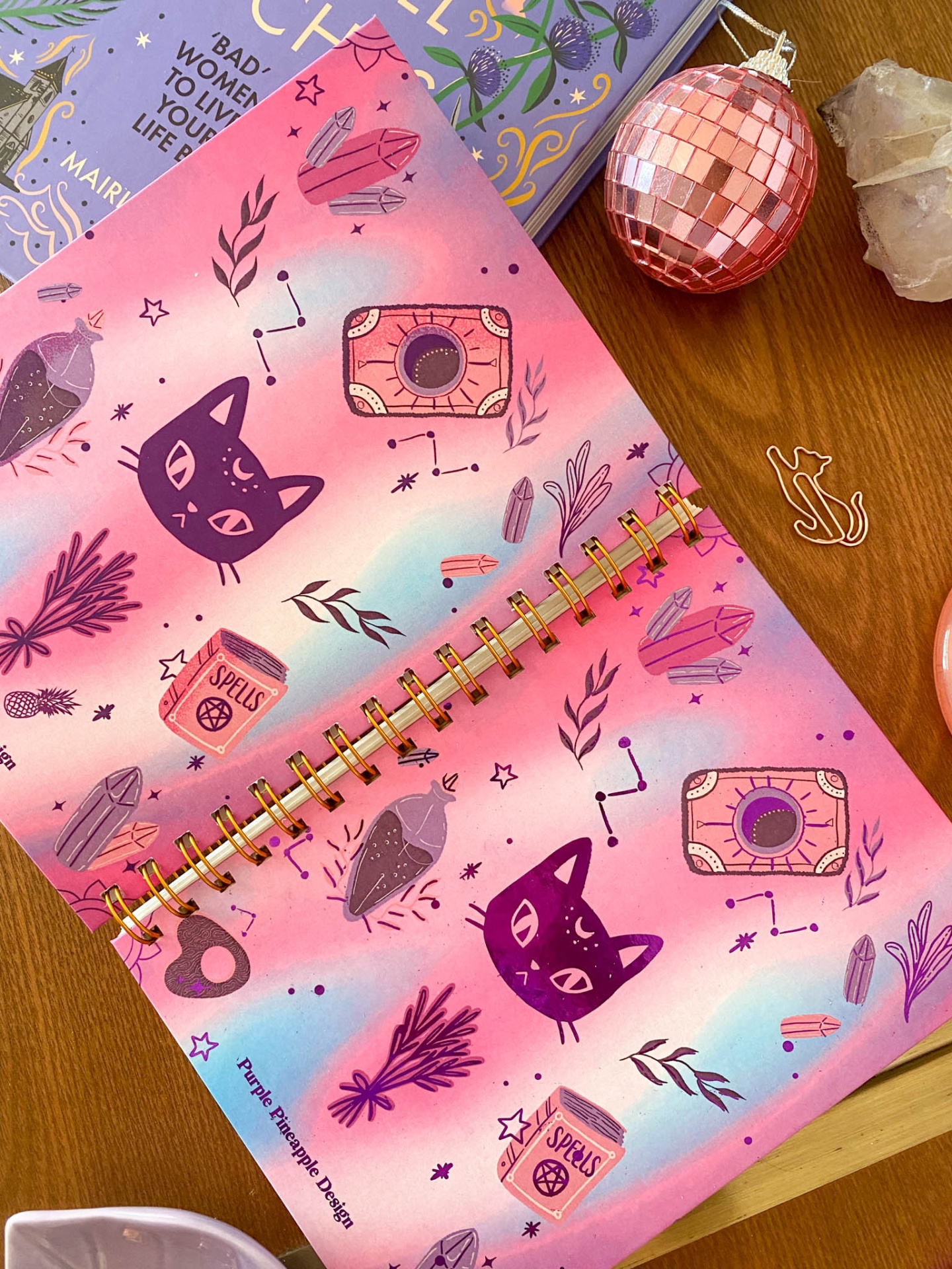 Agenda decorada com padrões de gatinhos pretos, cristais e símbolos astrológicos em tons rosa, azul e roxo