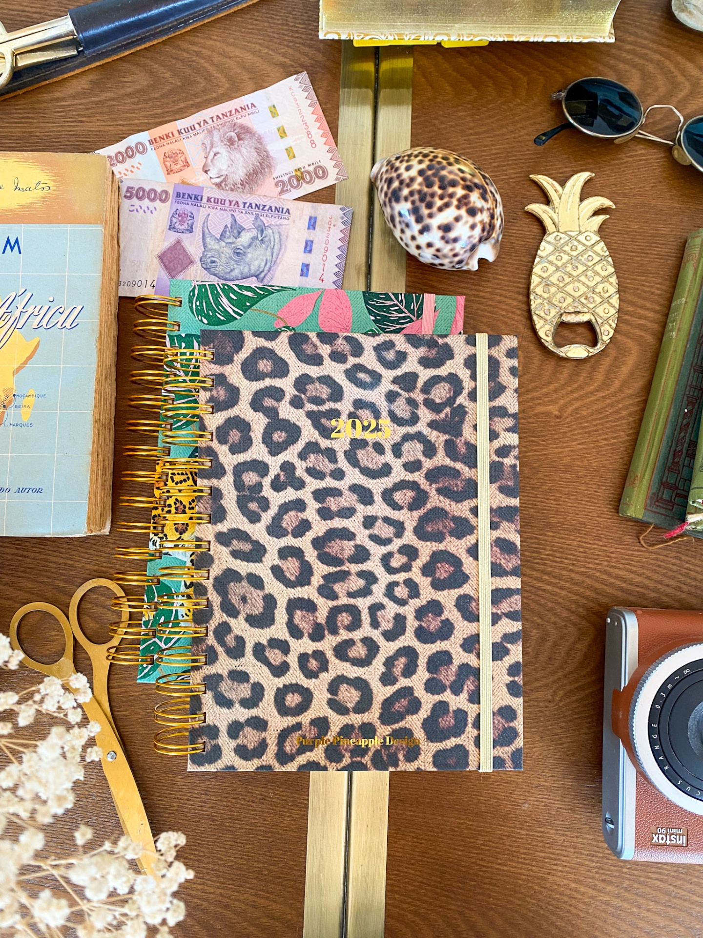 Agenda 2022 com padrão leopardo e objetos variados numa mesa de madeira