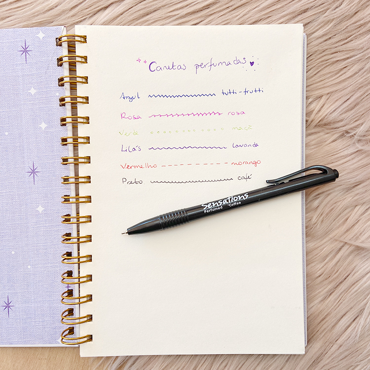 Caderno lilás com estrelas e caneta preta Sensations Premium sobre mesa clara