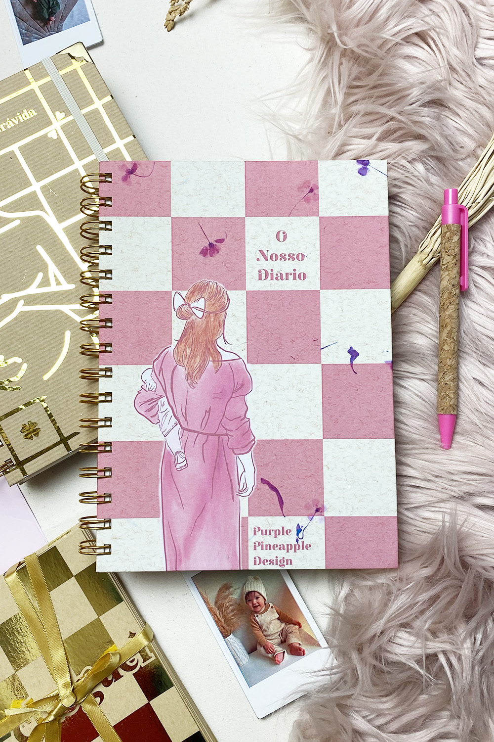 Caderno de capa xadrez rosa e branco com ilustração de mulher e textos O Nosso Diário e Purple Pineapple Design.
